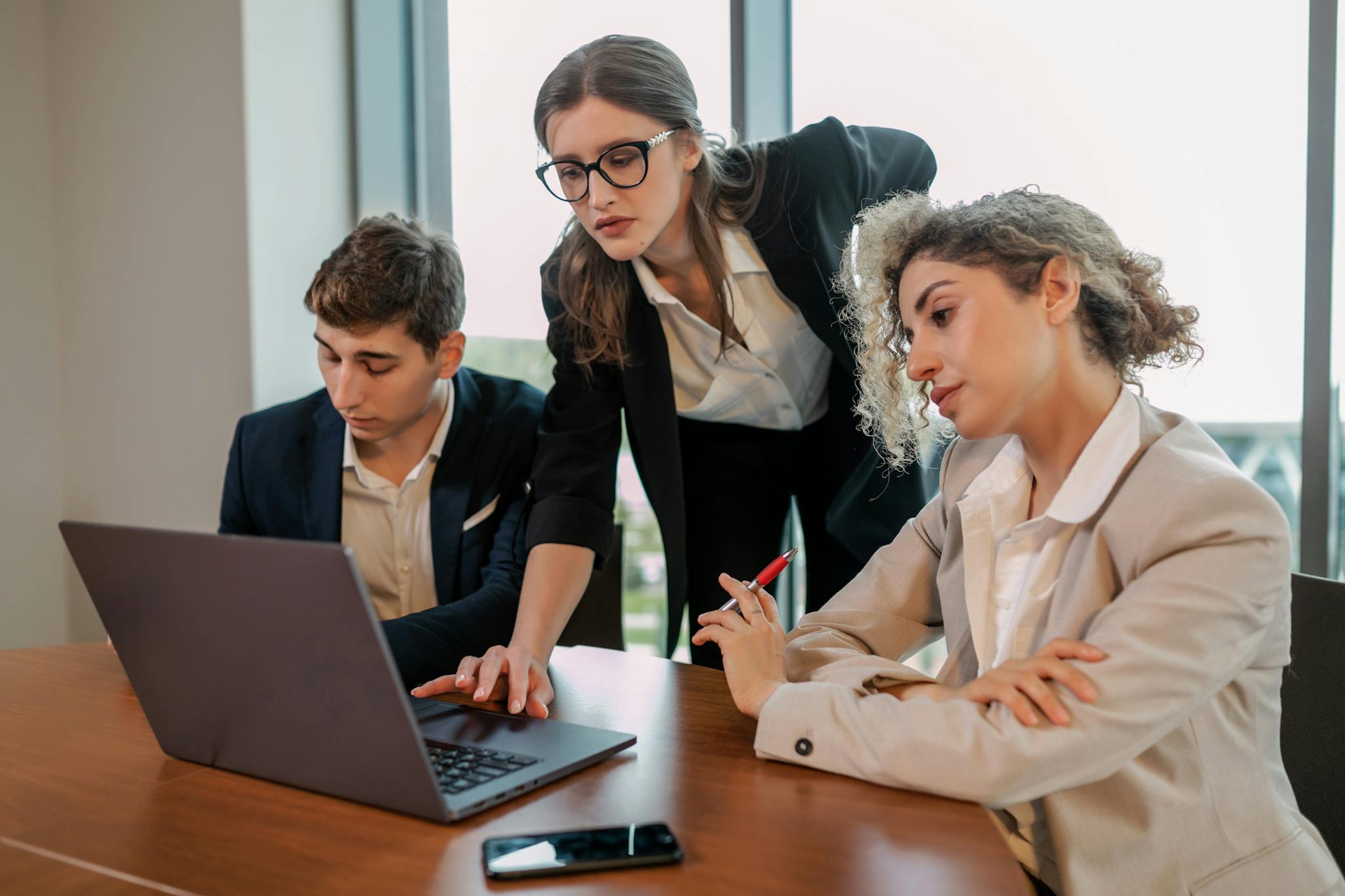 Diverse team working on a project together at an office desk with a laptop.